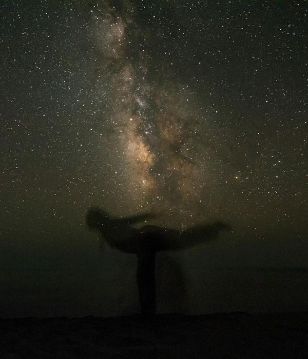 Silhouette of a person in a powerful yoga pose against a calm background.